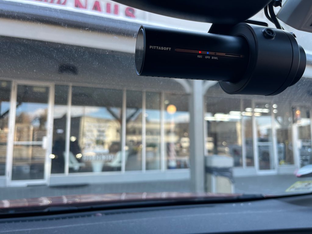 A camera mounted to the front windshield of a car, as seen from inside the car