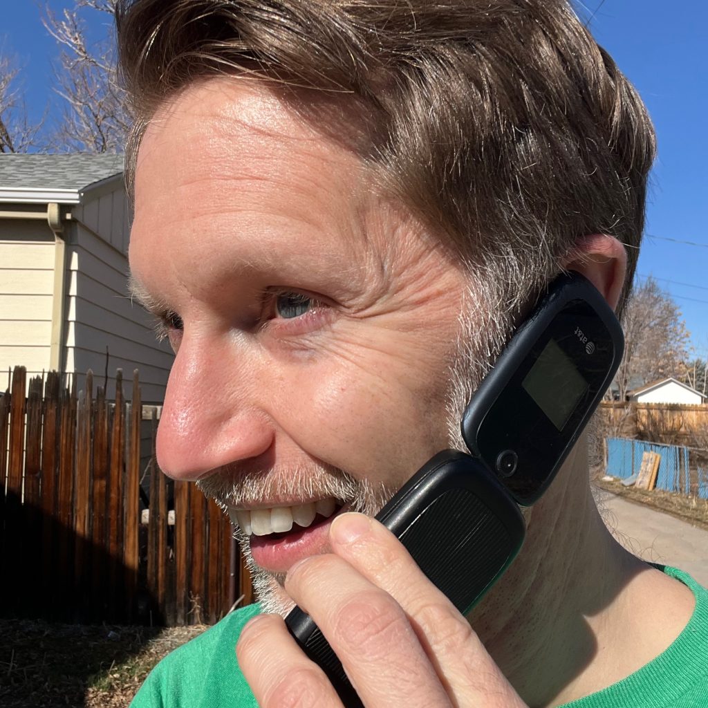 Profile picture of a white dude talking on an old-school cellular flip phone