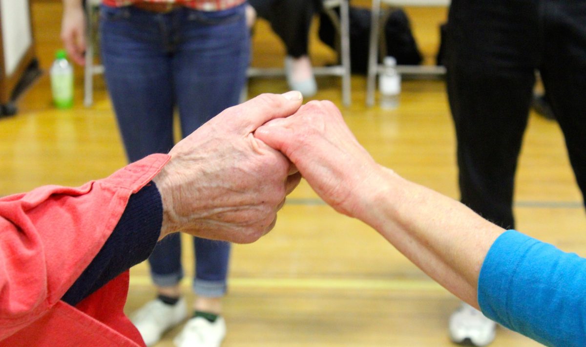A close-up of of two people's hands holding each other before a dance
