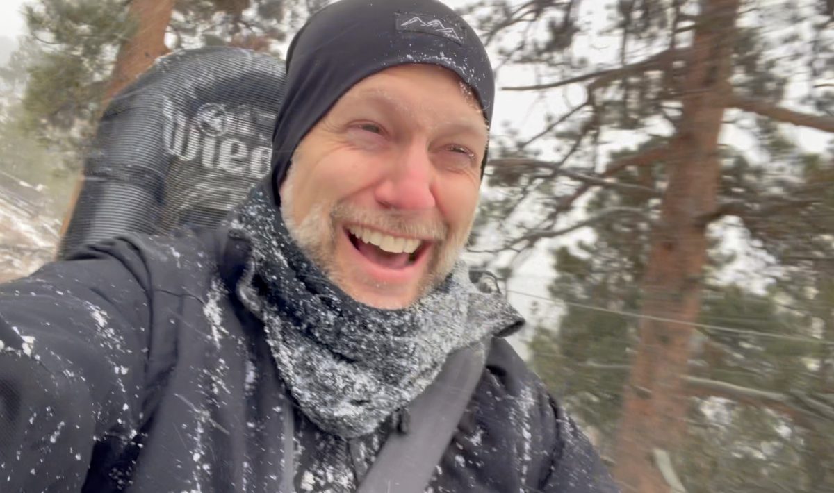 Ken seated in a coaster riding down a forested mountain in a blizzard